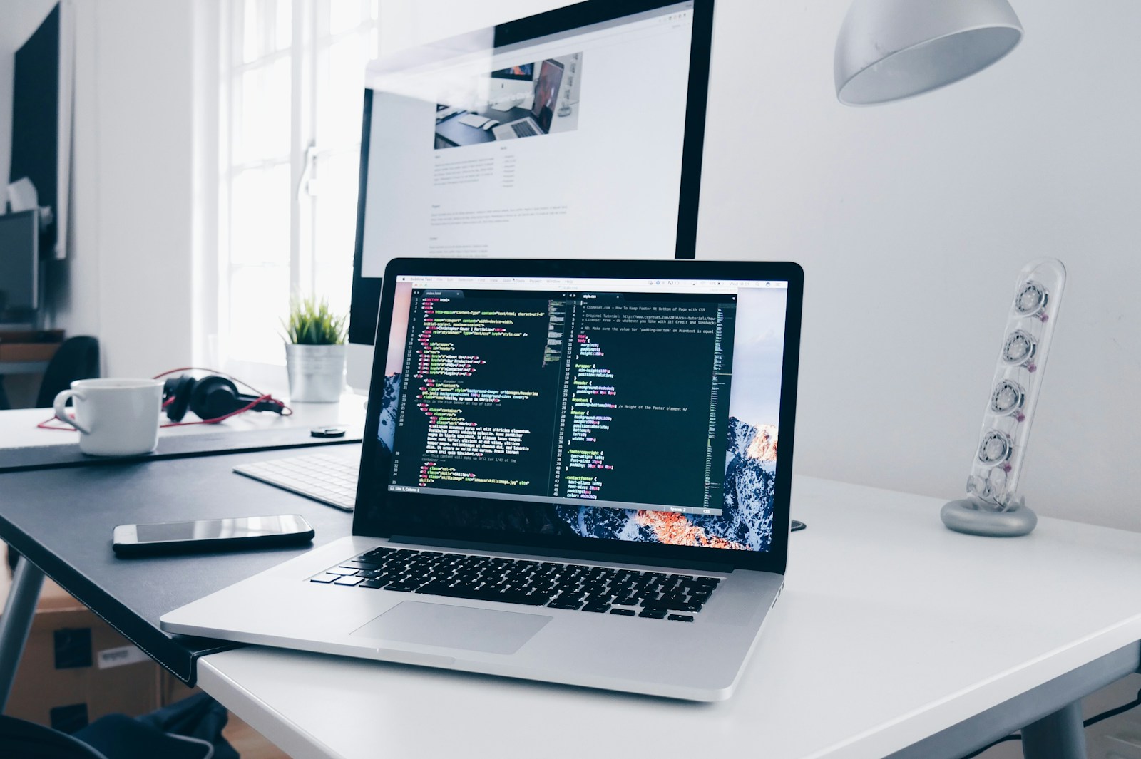 Developer workspace with laptop showing application code in a modern office
